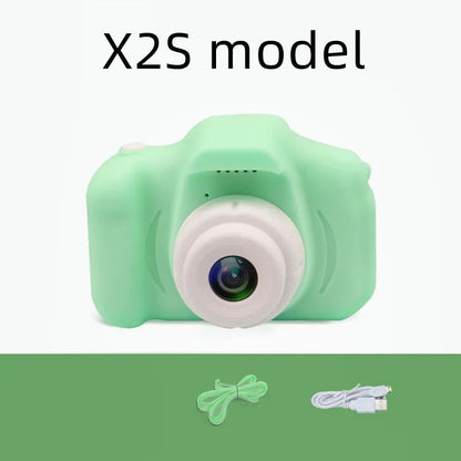 X2 HD mini digital camera for kids in silicone case with lanyard, shown capturing photo on 2-inch screen.