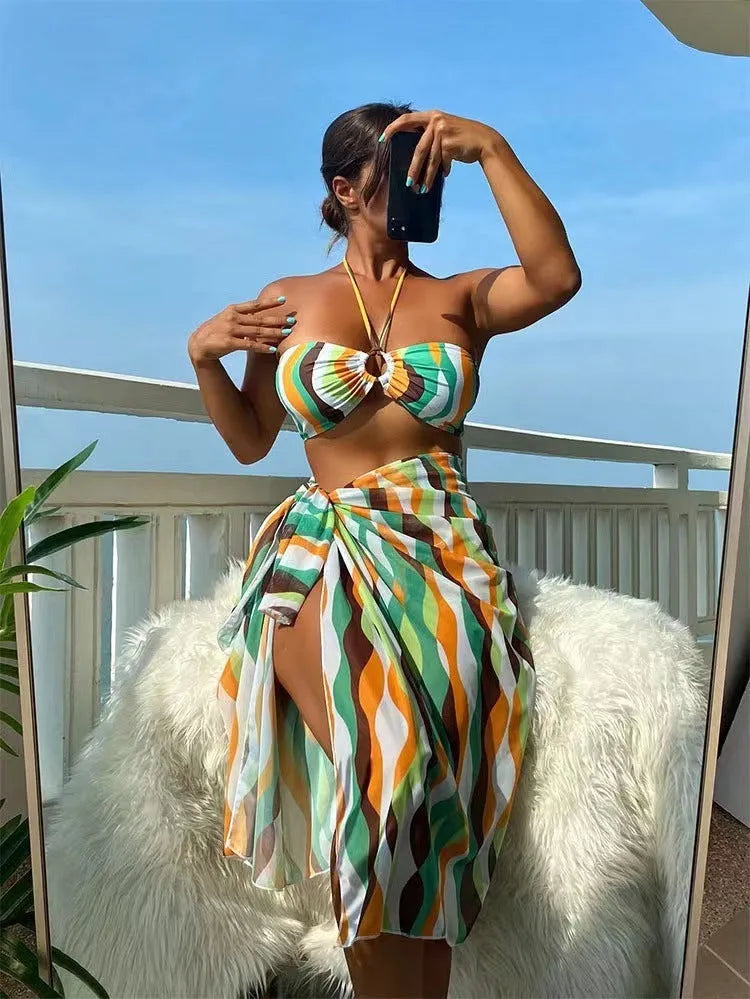 Women's three-piece swimwear set showing bikini top, briefs and printed beach skirt in polyester fabric