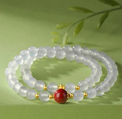 Close-up of a women's double layer bracelet with polished white agate and jequirity bean beads.