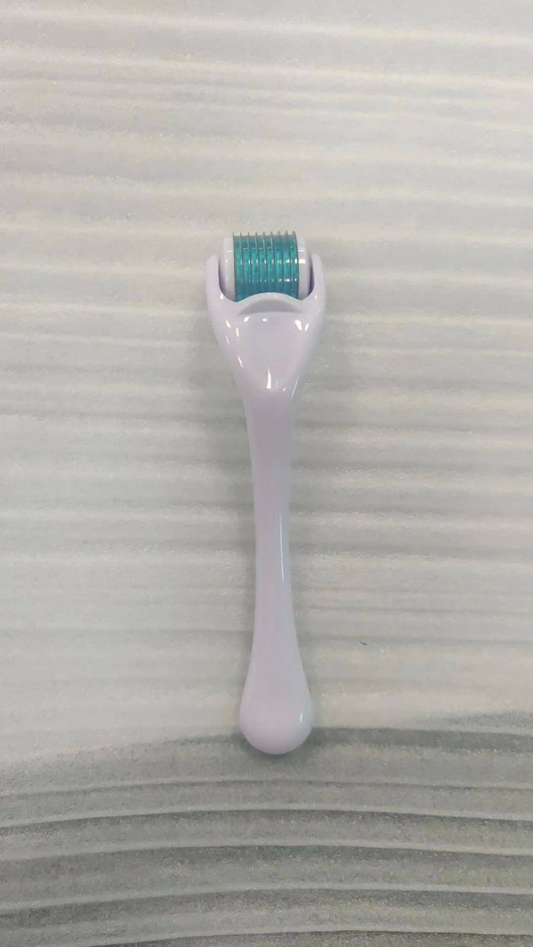 Sterile micro needle derma roller with black handle and coloured wheel on white background