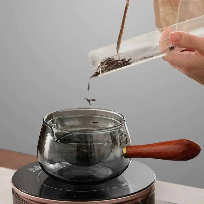 Elegant rotating glass teapot with wooden handle for a flavorful and visually appealing tea brewing experience