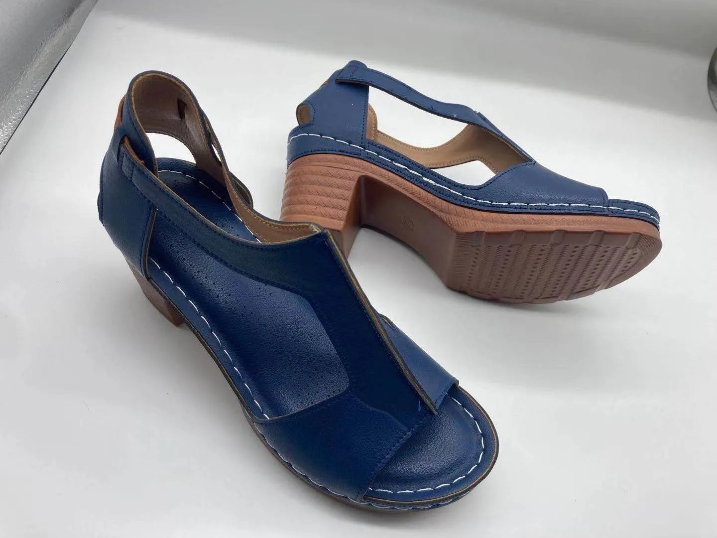 Women's beige peep toe wedge sandals with a buckle strap and low heel on a white background.