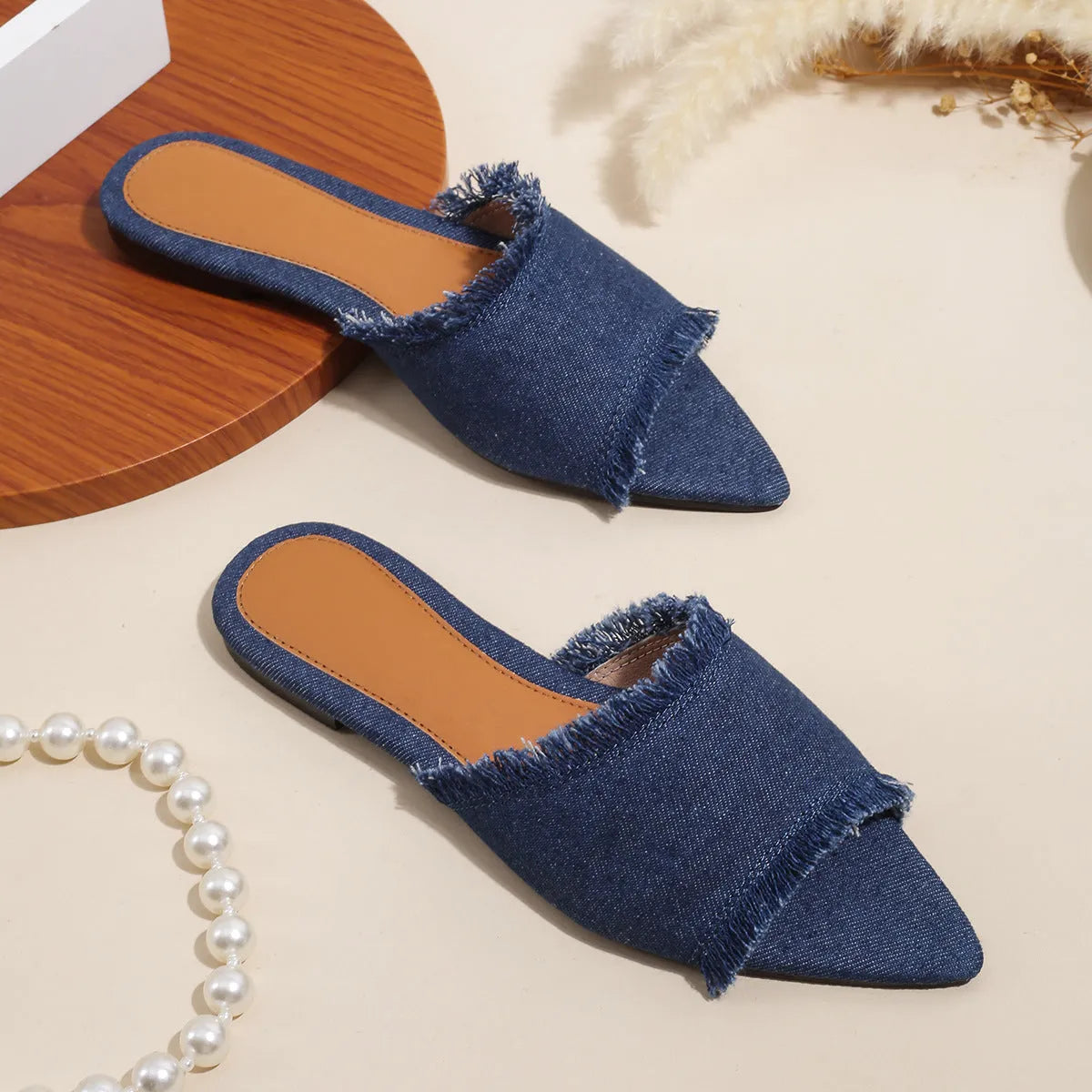 Women's denim flat slippers with tassel detail in apricot colour, showing leather lining.