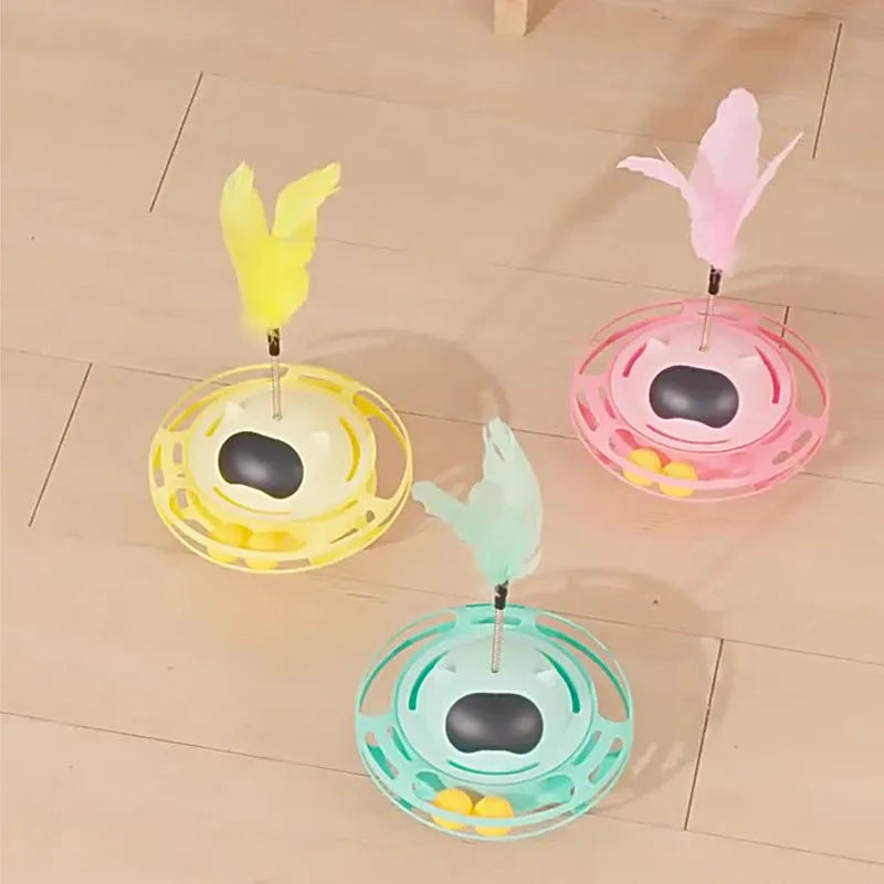 Pink self-hi tumbler cat toy with plush element on a turntable base, next to a play stick.