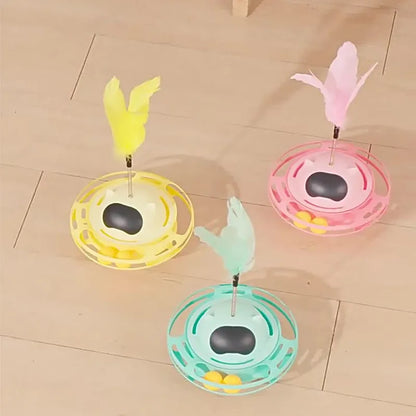 Pink self-hi tumbler cat toy with plush element on a turntable base, next to a play stick.