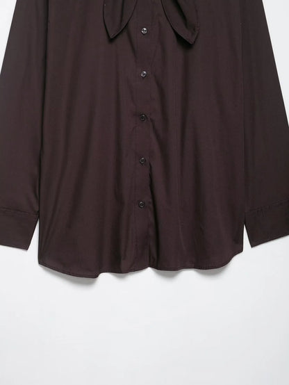 Brown women's loose-fit poplin shirt with long sleeves and an attached bow tie scarf.