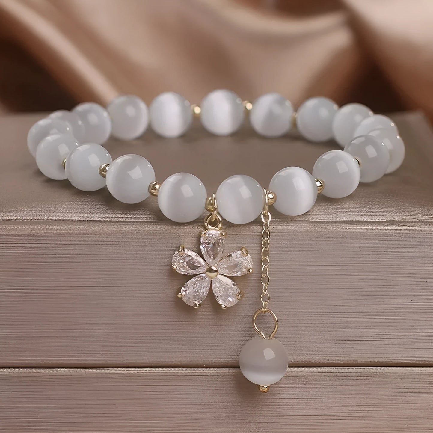 Women's white cat's eye crystal bracelet with flower tassels and a morganite safety buckle pendant.