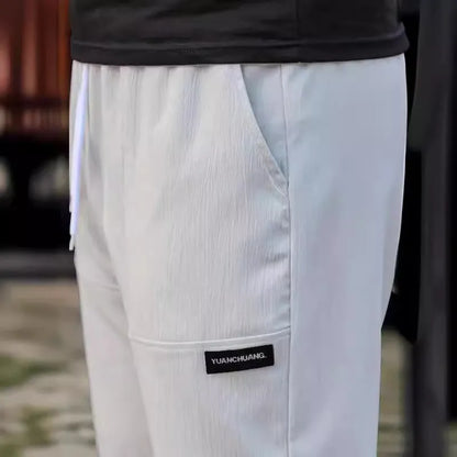 Men's light grey polyester trousers with an elasticated waistband laid flat