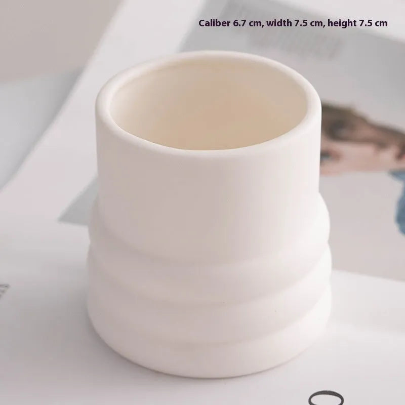 Set of ten round white ceramic candlesticks with minimalist relief patterns on a dining table
