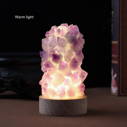 Mini USB night light glowing inside a natural amethyst crystal vug geode on a dark surface.