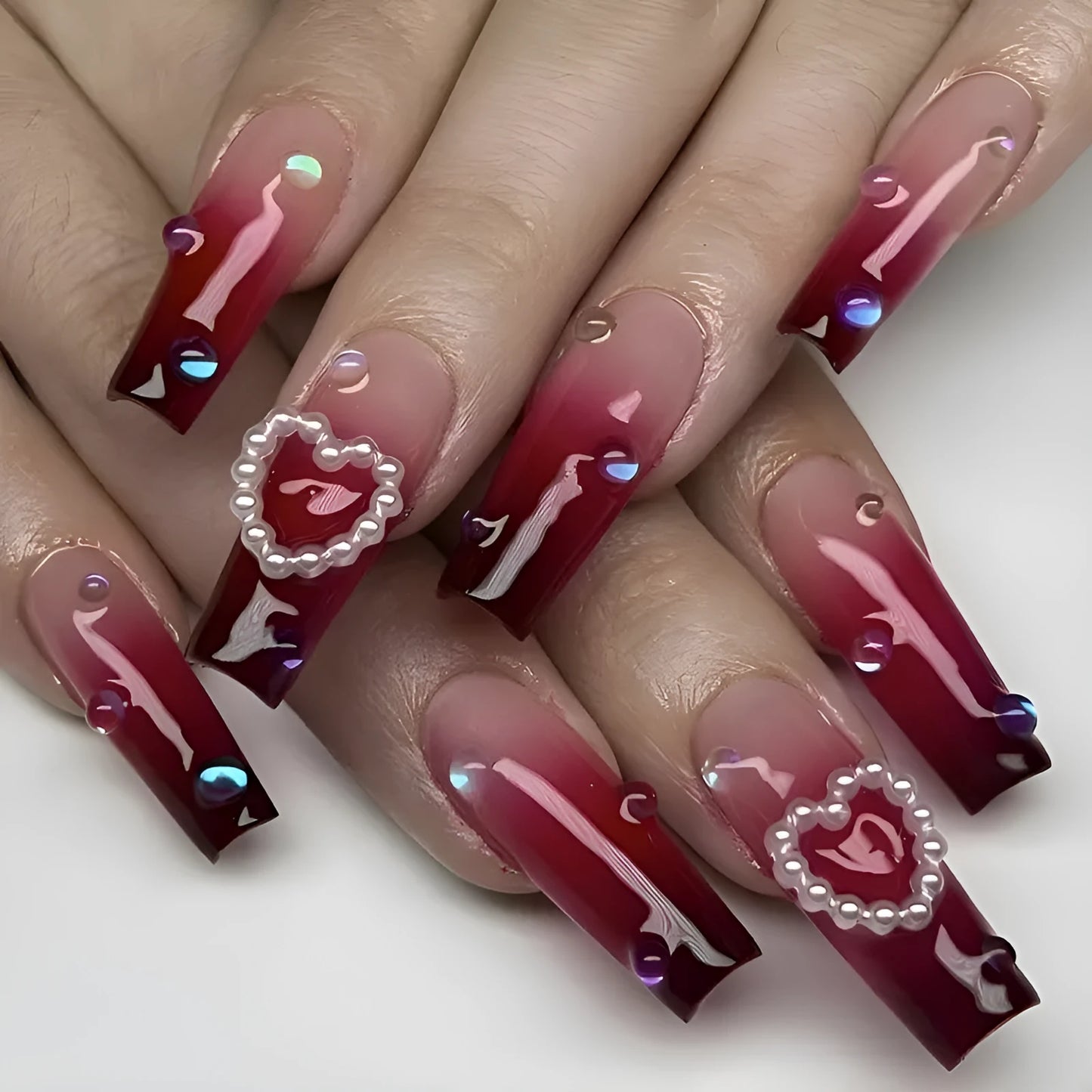 Set of long false nail tips with wine red gradient colour, plaid pattern, and a pearl heart design.
