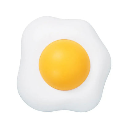 Fried egg shaped plush cat toy stuck to a window with a cat paw batting the 360-degree rotating ball.