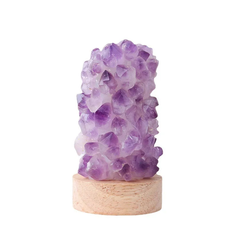 Mini USB night light glowing inside a natural amethyst crystal vug geode on a dark surface.