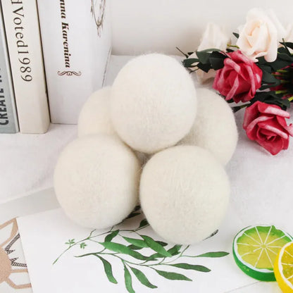 A 100% wool drying ball for laundry next to a plain cotton storage bag on a background.