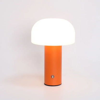 A small white USB and plug-in table lamp with a cylindrical shade, sitting on a wooden desk next to a laptop.