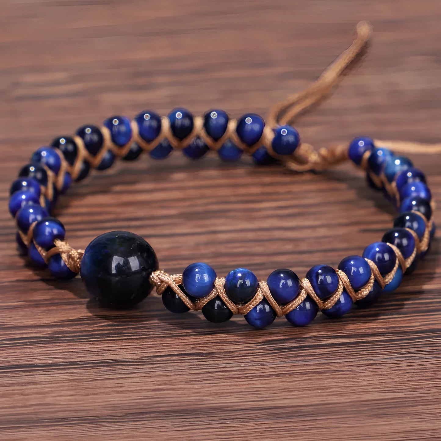 Close-up of a hand-woven geometric bracelet with a blue Tigereye stone on a wrist.