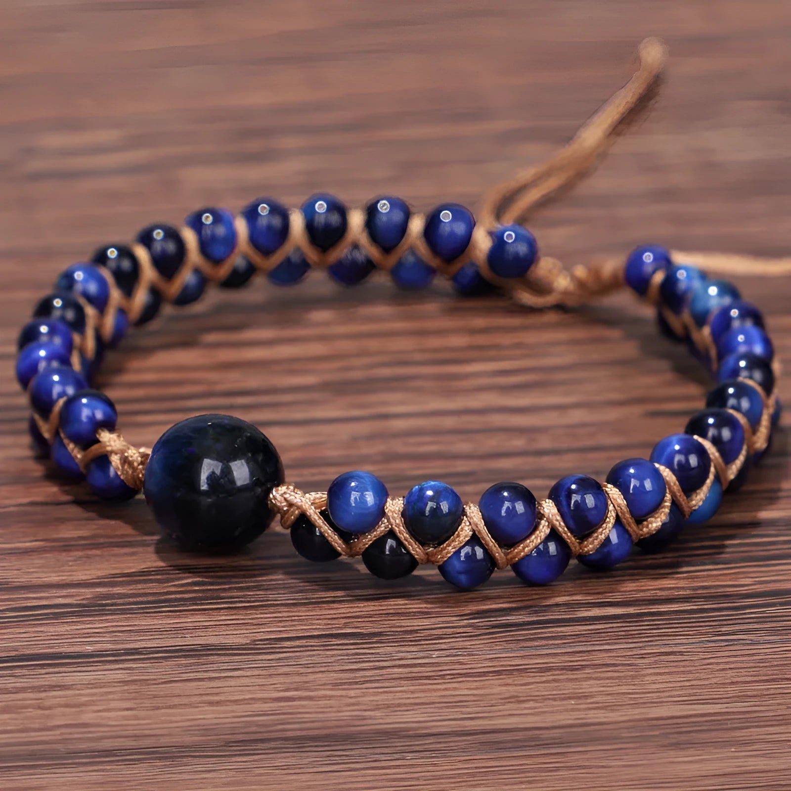 Close-up of a hand-woven geometric bracelet with a blue Tigereye stone on a wrist.