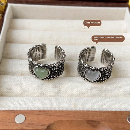 Retro style wide silver heart shape ring with adjustable band on a wooden surface