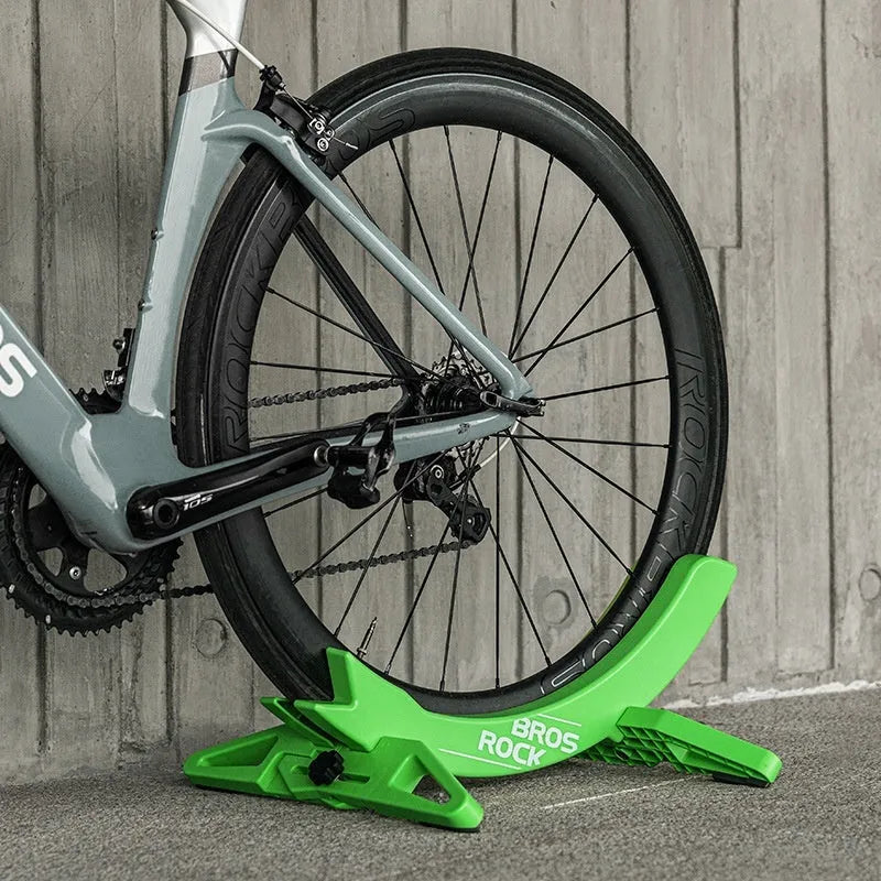 A black wall-mounted ABS plastic bracket holding a mountain bike vertically for storage.