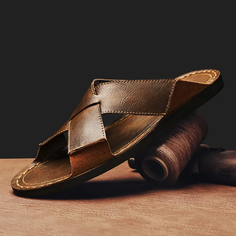 Men's black frosted pigskin leather slip-on sandals with a sewn rubber sole on a beach background.
