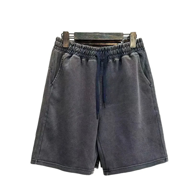 Man wearing loose-fit, straight-leg distressed cotton shorts in a solid colour
