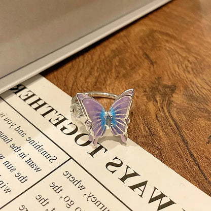 Copper butterfly women's ring with an open loop design on a plain background.
