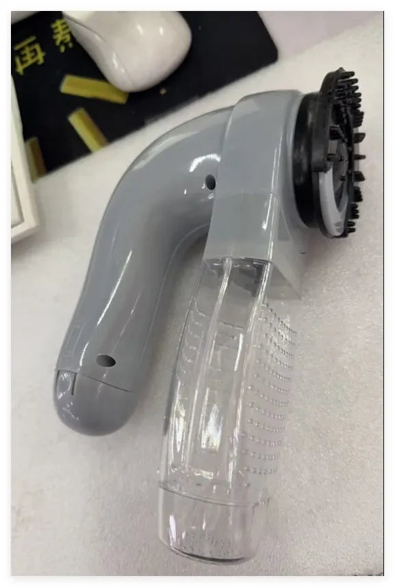 Grey handheld electric pet hair remover brush with soft rubber head for grooming dogs and cats.