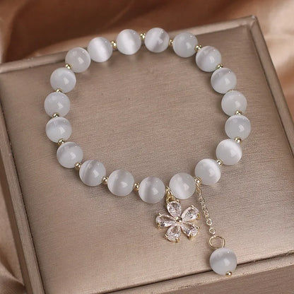 Women's white cat's eye crystal bracelet with flower tassels and a morganite safety buckle pendant.