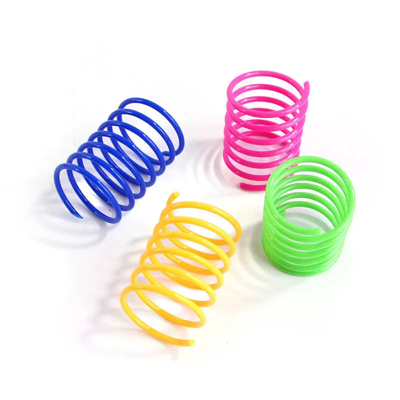 Assortment of colourful plastic coil spring toys for cats on a plain surface.
