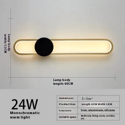Modern black wall lamp with a long adjustable arm and round shade, mounted beside a bed.