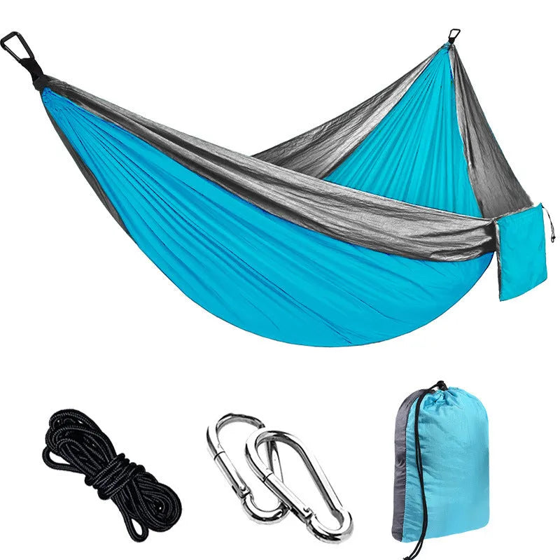 Parachute cloth double camping hammock in chosen colour, with black buckles and round ropes on a tree.