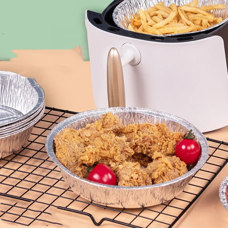 Round disposable aluminium foil liners for air fryers in four different sizes on a kitchen counter.