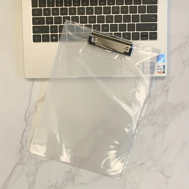Transparent A4 plastic plate holder with metal clip, holding white paper, on a desk.