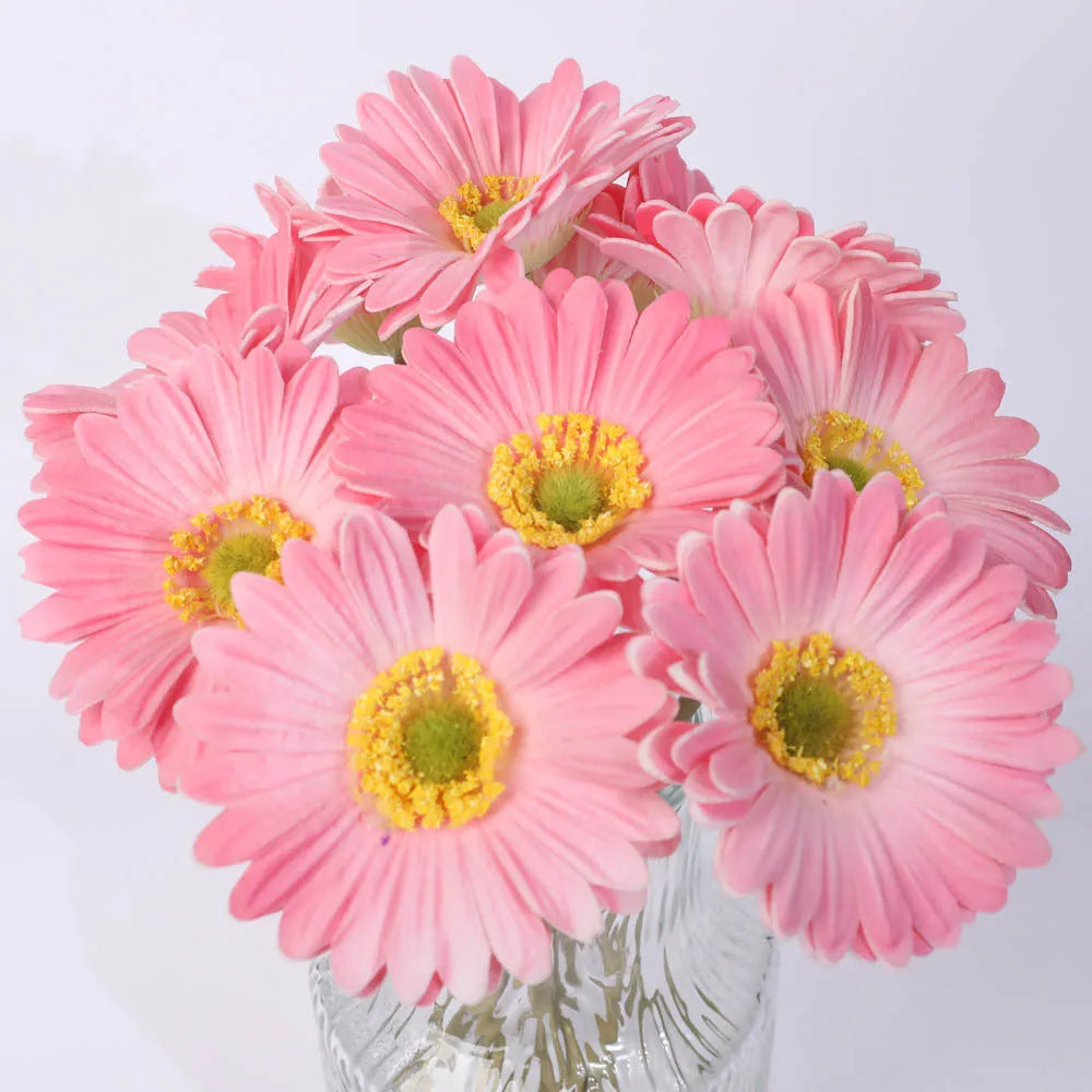 Silk artificial flower bouquet in a white polyurethane pot on a wooden table.