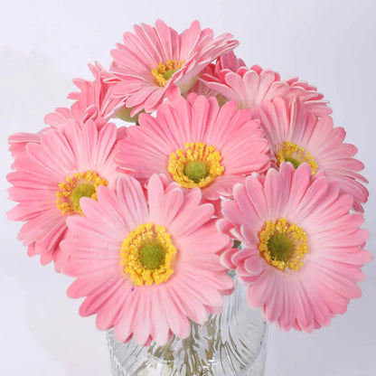 Silk artificial flower bouquet in a white polyurethane pot on a wooden table.