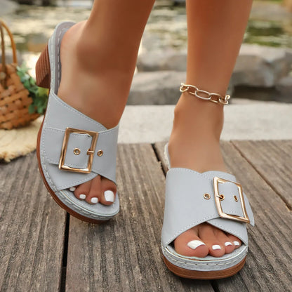 Women's black chunky heel slippers with a metal buckle and round toe, on a rubber sole