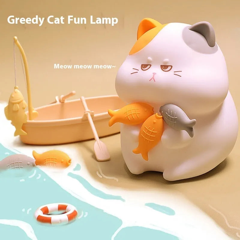 Yellow cartoon Greedy Cat desktop night light with plug, shown on a wooden desk.
