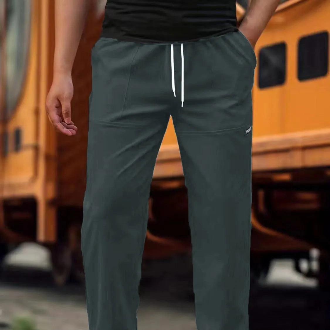 Men's light grey polyester trousers with an elasticated waistband laid flat