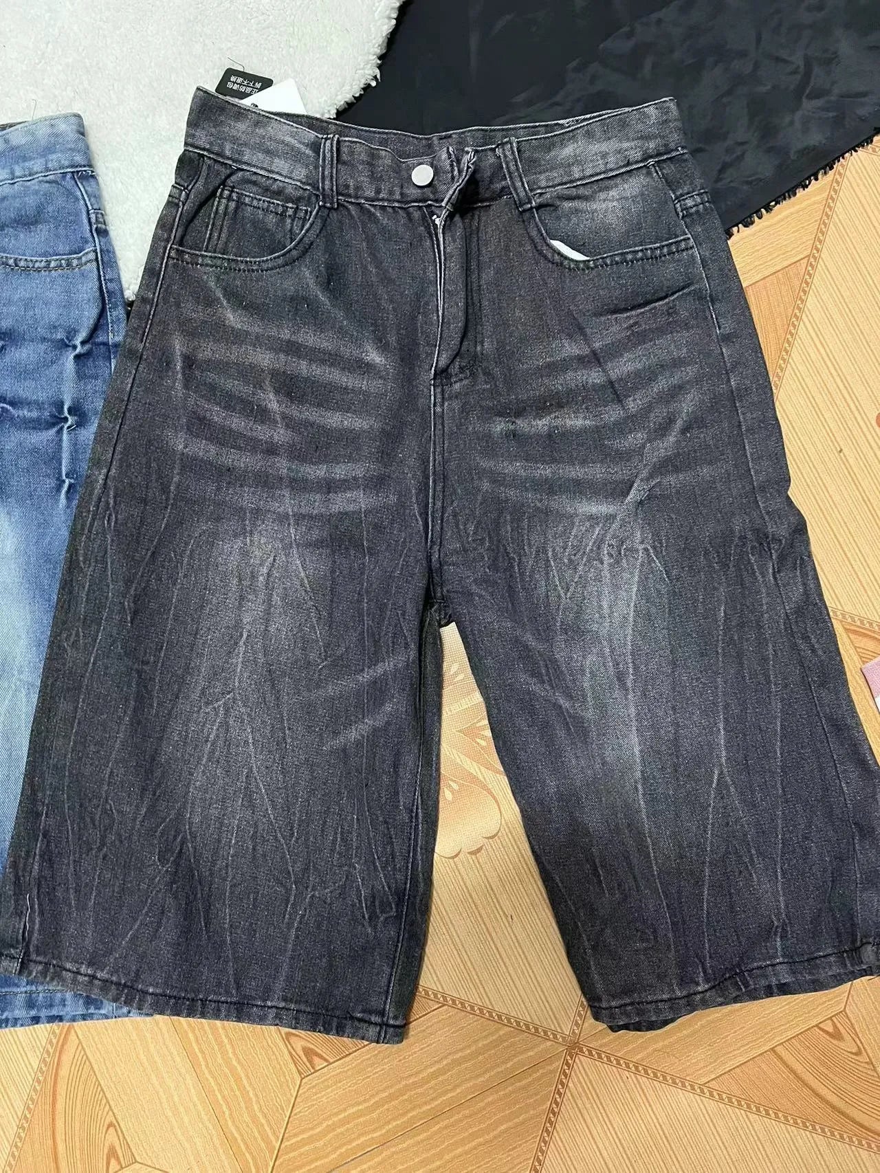 Man wearing loose light blue washed denim shorts with a straight leg and cropped length.