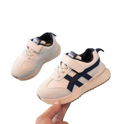 Children's white synthetic leather sneaker with Velcro strap on a non-slip rubber sole.
