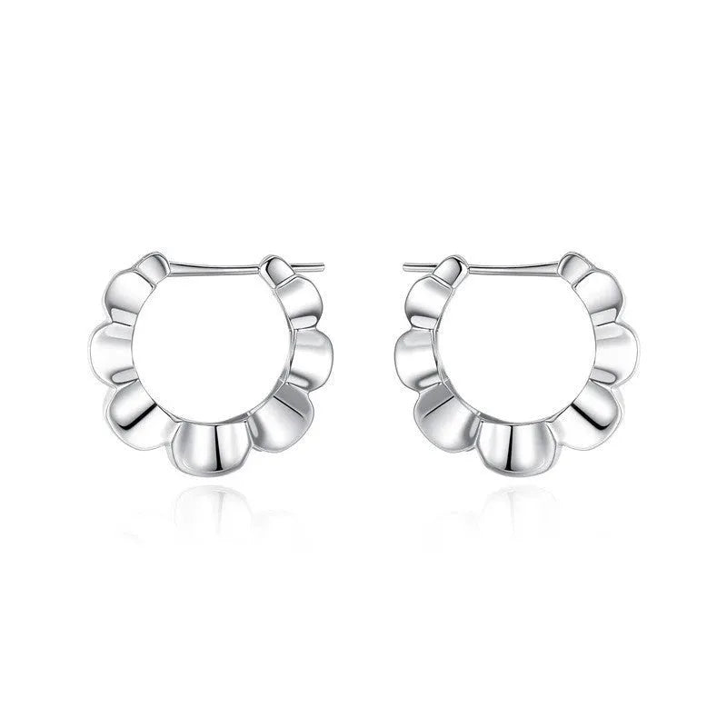 A pair of shiny silver geometric stud earrings with a round design on a plain background.