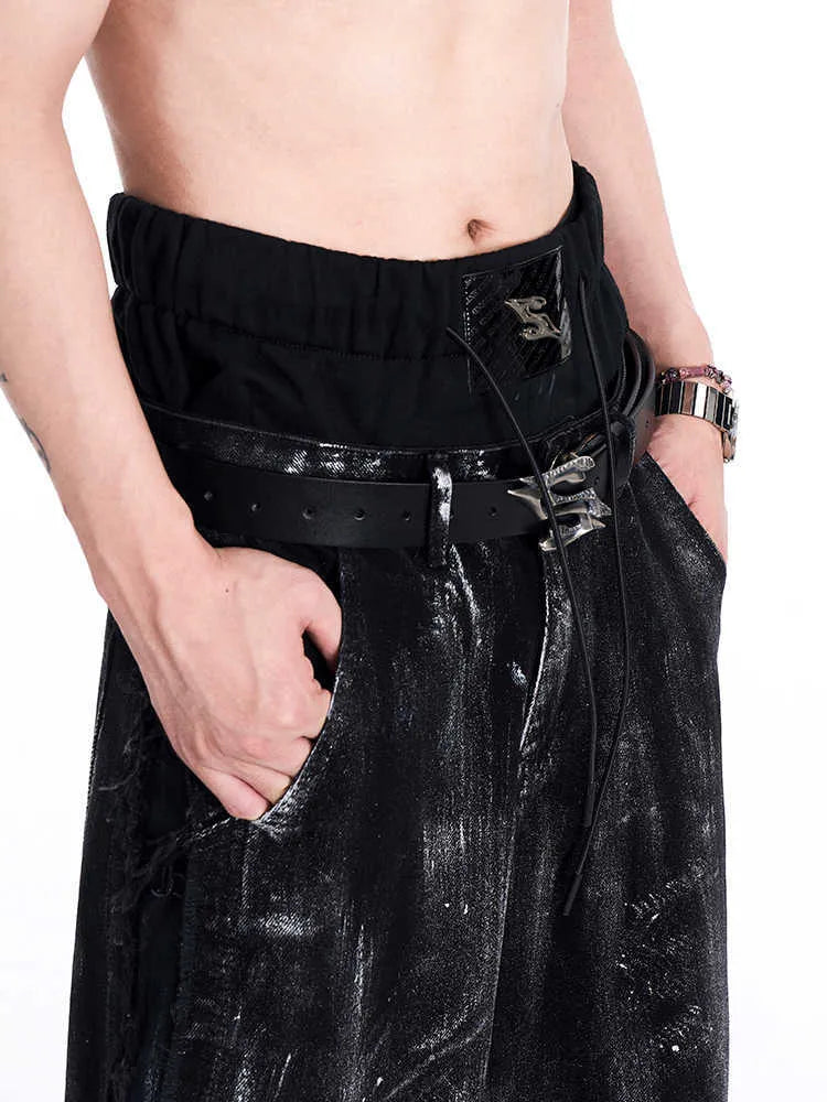Men's black leather belt with a silver metal letter-design buckle on a flat surface.