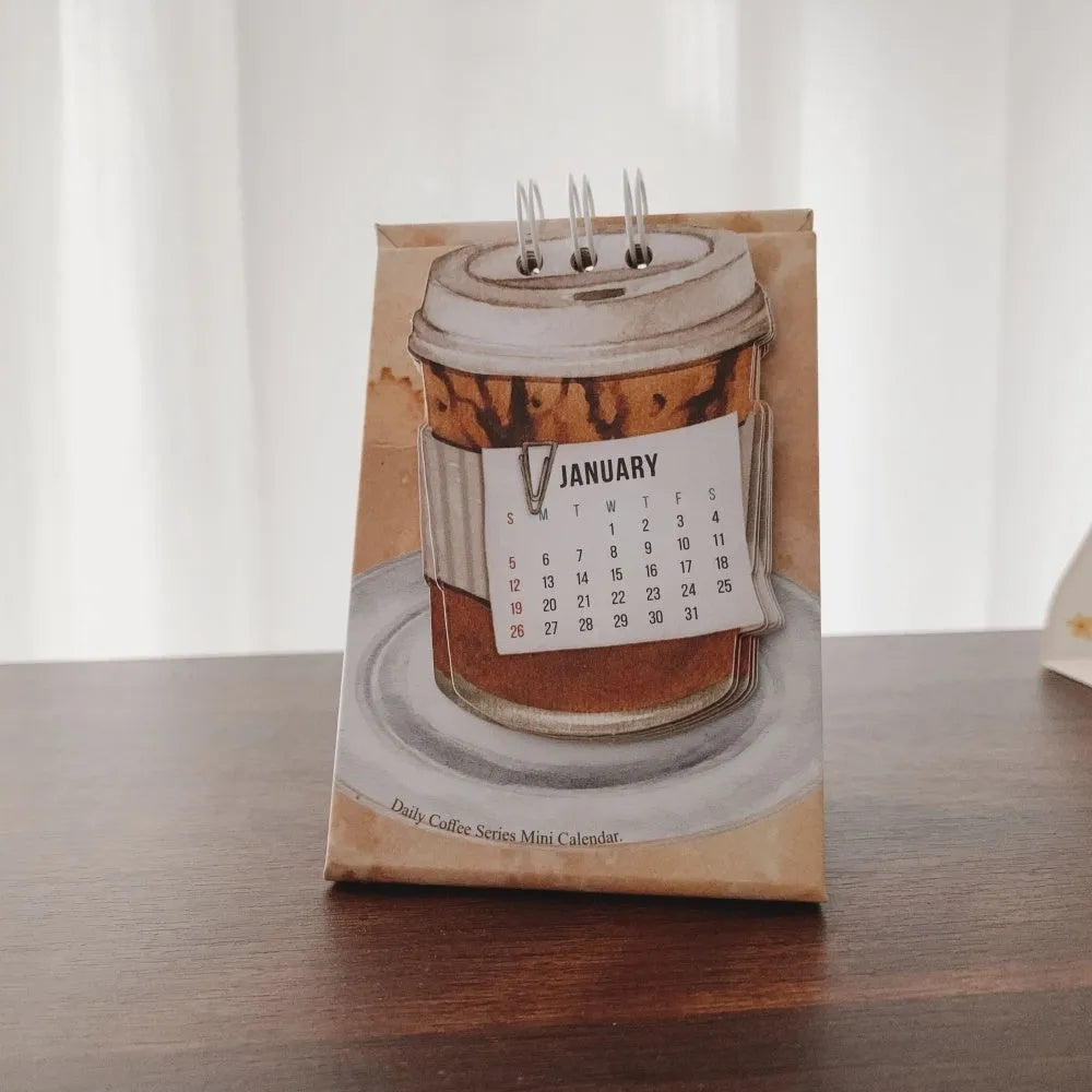Set of four different themed 2025 mini paper desk calendars on a desk.