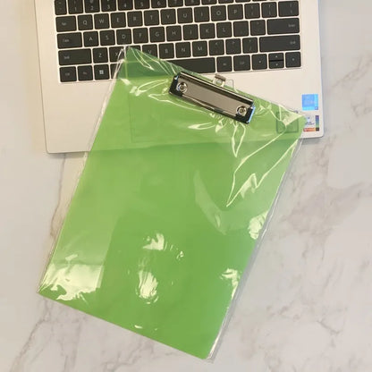 Transparent A4 plastic plate holder with metal clip, holding white paper, on a desk.