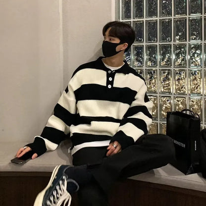 Man wearing a loose grey and black striped long sleeve pullover sweater.