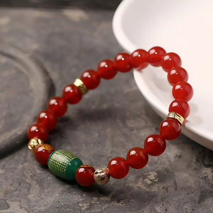 A red agate beaded bracelet with a Guanyin pendant on a white background.
