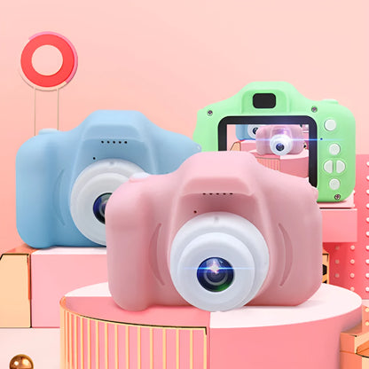X2 HD mini digital camera for kids in silicone case with lanyard, shown capturing photo on 2-inch screen.