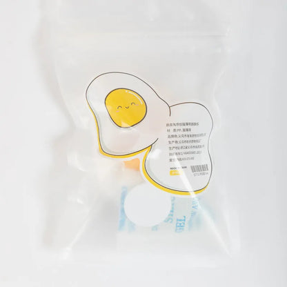 Fried egg shaped plush cat toy stuck to a window with a cat paw batting the 360-degree rotating ball.