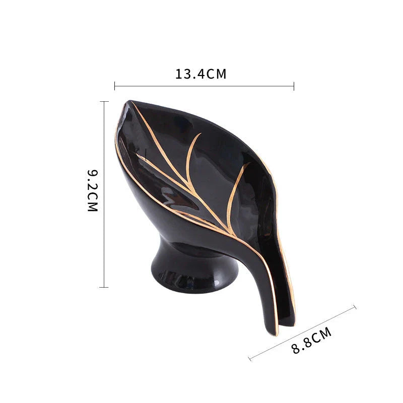 A ceramic soap dish with a sleek leaf-shaped design, featuring a suction cup base for secure and tidy placement in the bathroom or kitchen.