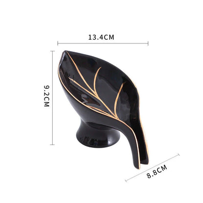 A ceramic soap dish with a sleek leaf-shaped design, featuring a suction cup base for secure and tidy placement in the bathroom or kitchen.